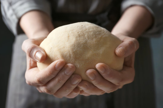 Woman holding raw dough in hands, closeup