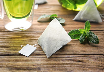 Paper teabag and mint leaves on wooden table. Weight loss concept
