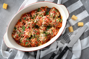 Ceramic casserole dish with turkey meatballs, tomato sauce and melted cheese on table