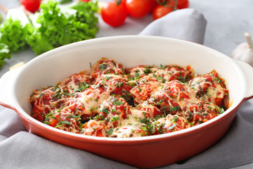 Ceramic casserole dish with turkey meatballs, tomato sauce and melted cheese on table