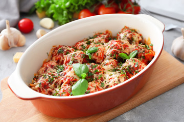 Ceramic casserole dish with turkey meatballs, tomato sauce and melted cheese on table