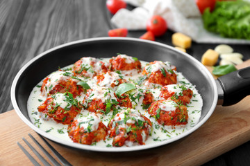 Frying pan with delicious turkey meatballs and sauce on table