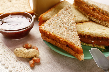 Tasty sandwiches with peanut butter and jam on table