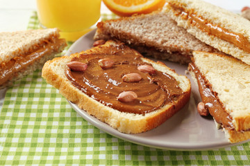 Tasty sandwiches with peanut butter on table