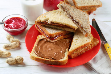Tasty sandwiches with peanut butter and jam on table
