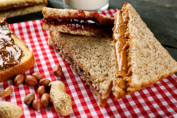 Tasty sandwiches with jam and peanut butter on table