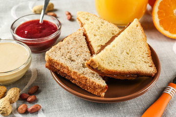 Tasty sandwiches with peanut butter and jam on table