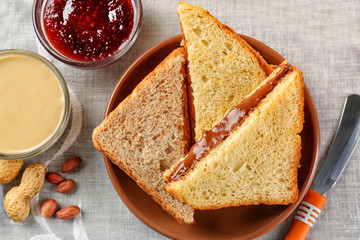 Tasty sandwiches with peanut butter and jam on table