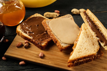 Tasty sandwiches with peanut butter on wooden board