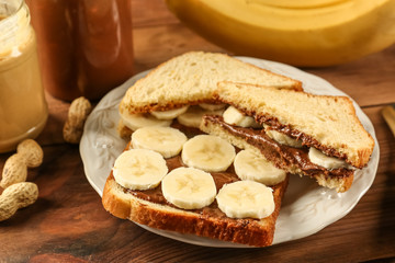 Tasty sandwiches with peanut butter and sliced banana on plate