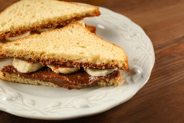 Tasty sandwiches with peanut butter and sliced banana on plate