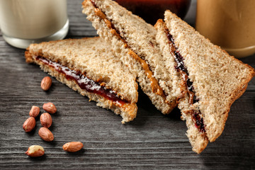 Tasty sandwiches with peanut butter and jam on table