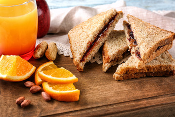 Tasty sandwiches with peanut butter and jam for breakfast on wooden board