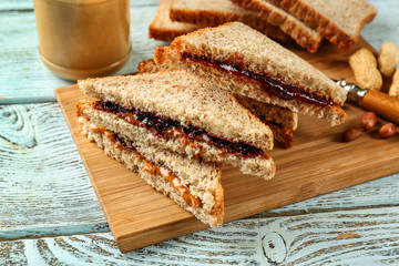 Tasty peanut butter and jelly sandwiches on wooden board