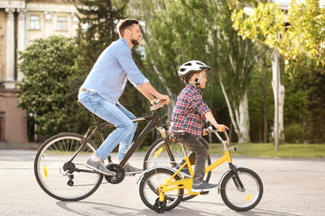 Fototapeta premium Dad and son riding bicycles outdoors