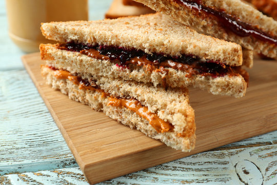 Tasty peanut butter and jelly sandwiches on wooden board