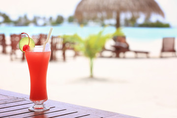Glass of tasty cocktail on table in beach cafe