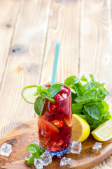 Summer drink with raspberries, lime and ice on a old wooden table