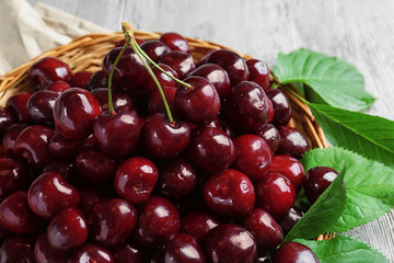 Wicker plate with fresh sweet cherries on table, closeup