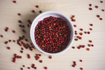 Red round peppercorns on wooden board