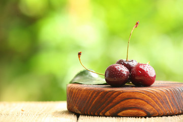 Wooden board with fresh cherry on table outdoors