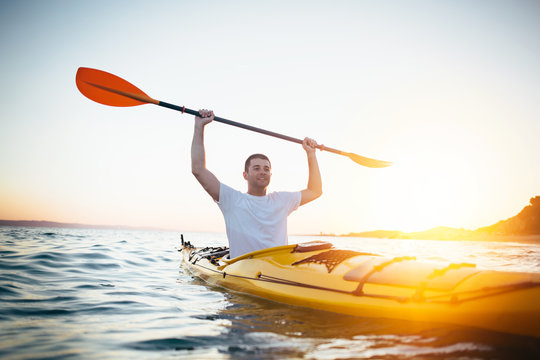 Kayaker man holding oars high. Success, achievement, winning concept