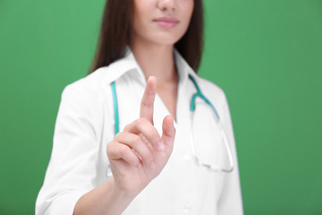 Young doctor using virtual screen, on color background