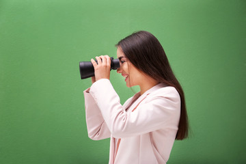 Beautiful young woman with binocular on color background