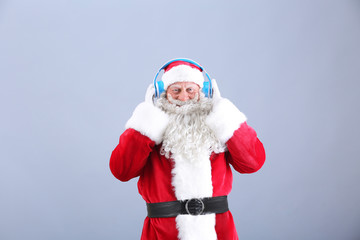 Santa Claus listening to music on color background