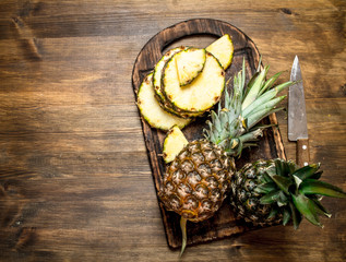 Sliced pineapple on a cutting Board with a knife.