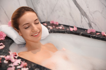Young beautiful woman relaxing in bath with foam