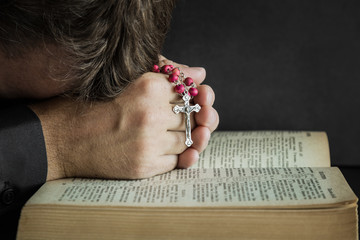 A front of the bible a man with cross in his hands praying a God. Prayer time on sunday.