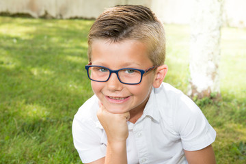 boy child with his glasses in the garden park of the house in summer