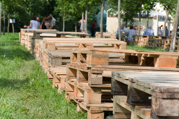 Fototapeta na wymiar Wooden pallets outdoors in a summer park against a background of green grass for a rest of people