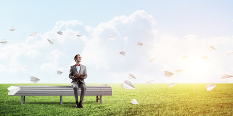 Young businessman or student studying the science and paper planes fly around