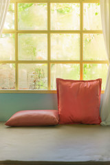 Beautiful pink pillows on sofa decoration living room with sun light from windows, morning in a rainy day.