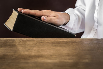 Man's hand swearing on the bible. Taking an oath.