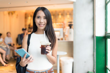 Woman holding iced coffee and cellphone