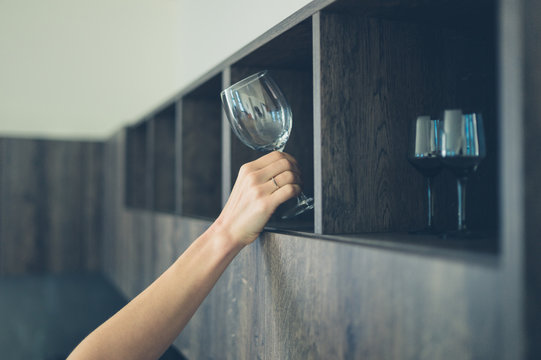 Young woman getting wine glass in kitchen