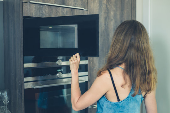 Young woman opening the microwave