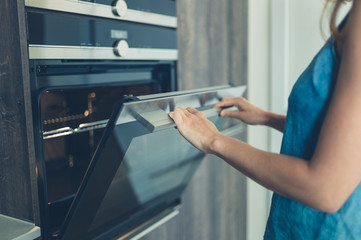 Young woman opening the oven
