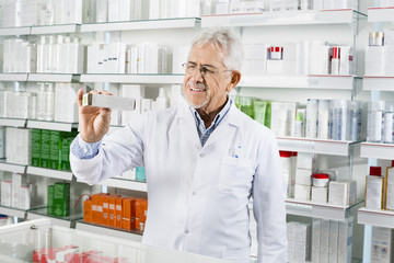 Senior Pharmacist Showing Medicine Box At Counter