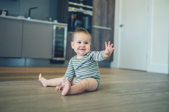 Little baby on kitchen floor waving