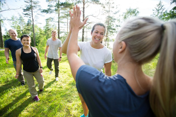Women Giving High-Five While Friends Walking At Forest