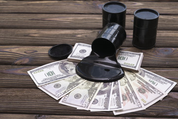 Barrels of oil on dollars on a wooden background.