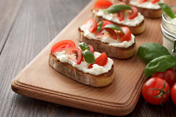 Homemade bruschetta with feta, basil and tomatoes on cutting board.