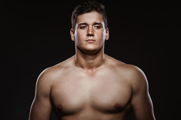 Fototapeta premium sports guy with a naked torso on a black background
