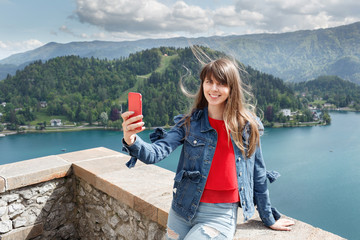 Girl taking selfie from castle top of the mountain with valley view and lake on the background....