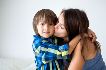 Portrait of beautiful pregnant mother with love hugging her precious son in the park
