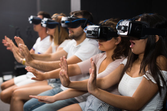 Woman is enjoying exciting movie with friends in VR glasses